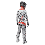 Motocrossförare sedd bakifrån bärandes Alpinestars 2024 Techstar Rantera-tröja och matchande byxor, Haze Gray Camo-mönster med framträdande röda Alpinestars-logotyper, svart hjälm, vita och svarta stövlar, svarta handskar, koordinerat set med motocrossutrustning.
