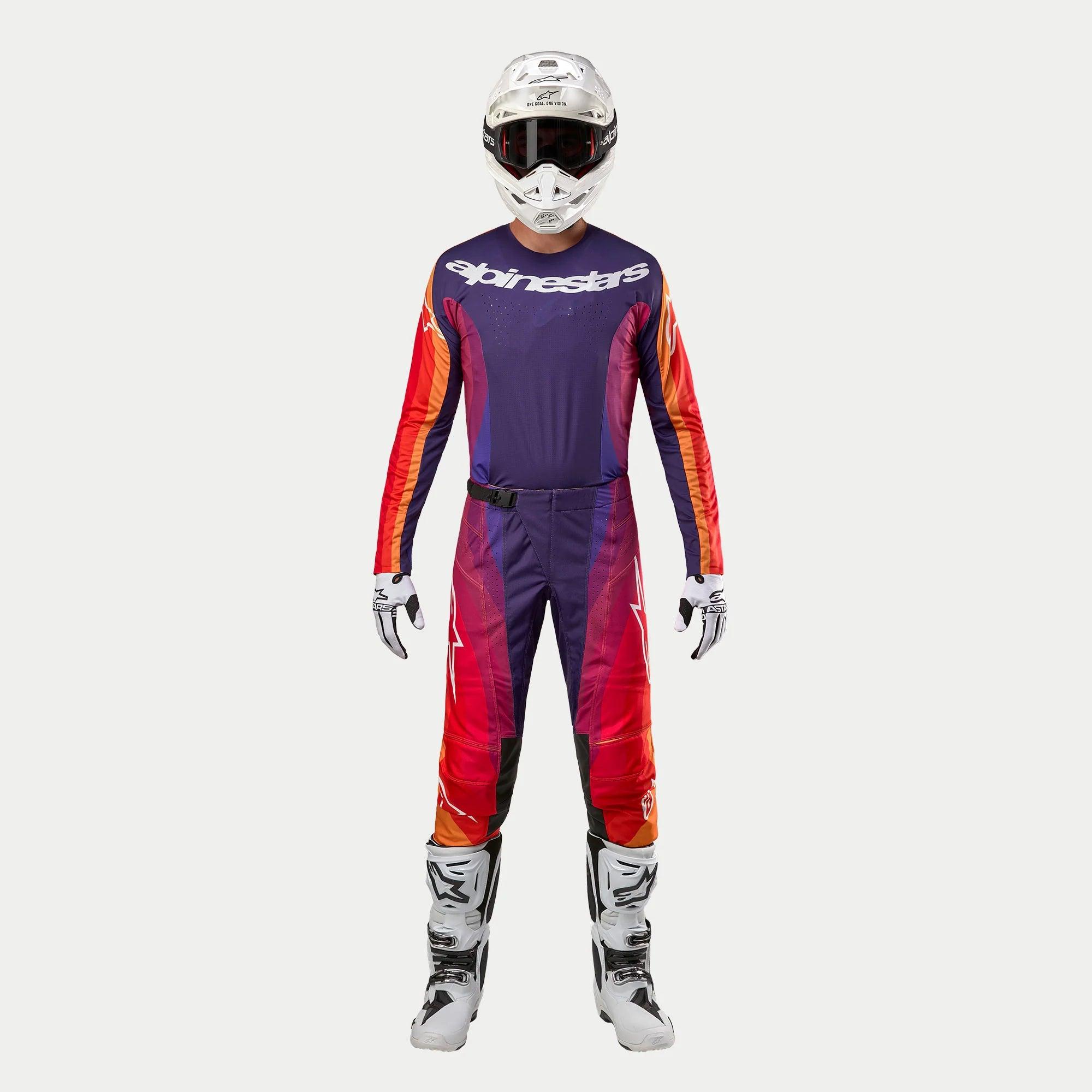 Alpinestars 2024 Techstar Pneuma motocrosskit, mörklila tröja med vit logotyp och orange ärmar, matchande byxor i lila, rött och orange, vit hjälm med goggles, vita stövlar och handskar, professionell outfit för terrängkörning