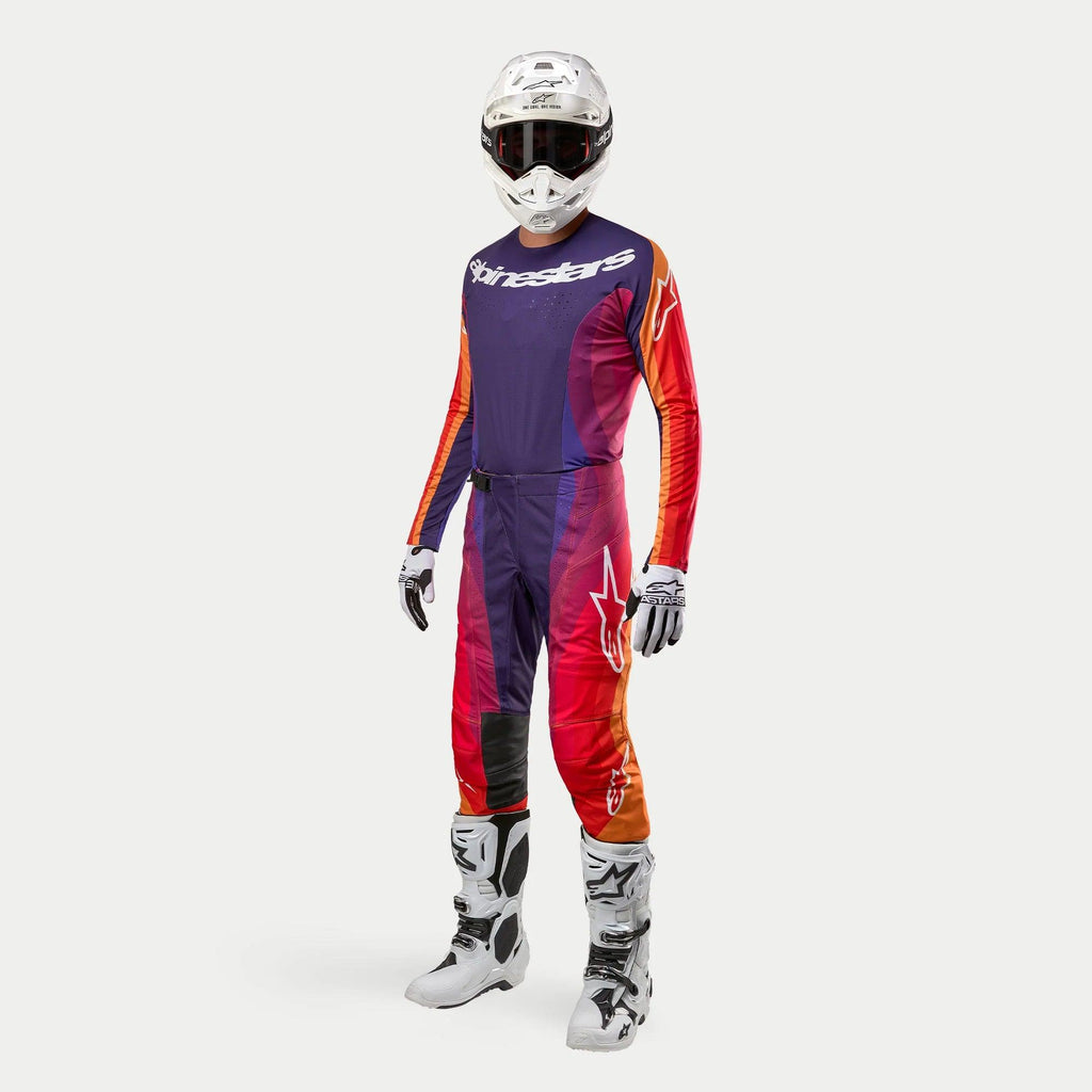 Alpinestars 2024 Techstar Pneuma motocross-set, komplett outfit med tröja och byxor i lila, orange och djupt blått, vit hjälm med svarta goggles, vita stövlar och handskar, professionell racingdesign för terrängkörning.