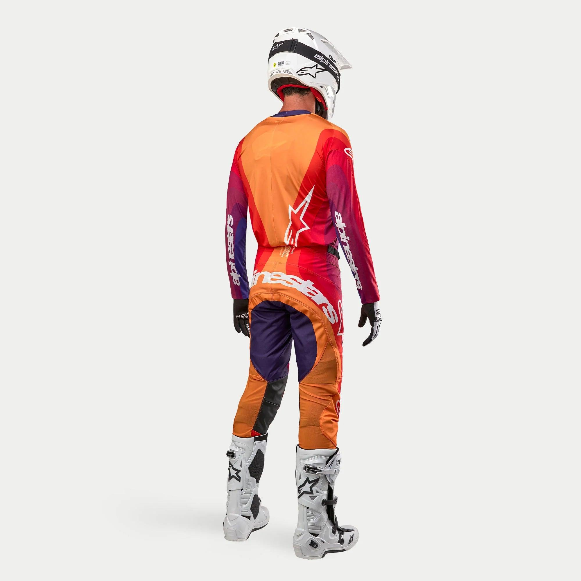 Alpinestars 2024 Techstar Pneuma motocross-set, komplett outfit för terrängkörning sett bakifrån, lila, orange och mörkblå design, vit stjärnlogotyp på ryggen, vit Alpinestars-text på byxorna, vit hjälm och vita stövlar