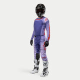 Alpinestars 2024 Techstar Ocuri motocross-set, lila tröja och byxor med starkt orangea logotyper och detaljer, svart hjälm med goggles, vita stövlar med svarta detaljer, svarta handskar, professionell utrustning för terrängkörning