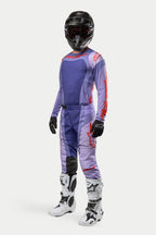 Motocrossförare klädd i Alpinestars 2024 Techstar Ocuri-tröja i Purple Hot Orange, matchande lila racingbyxor med orange detaljer, svart hjälm, vita och svarta stövlar och svarta handskar, komplett tävlingsutrustning för terrängkörning