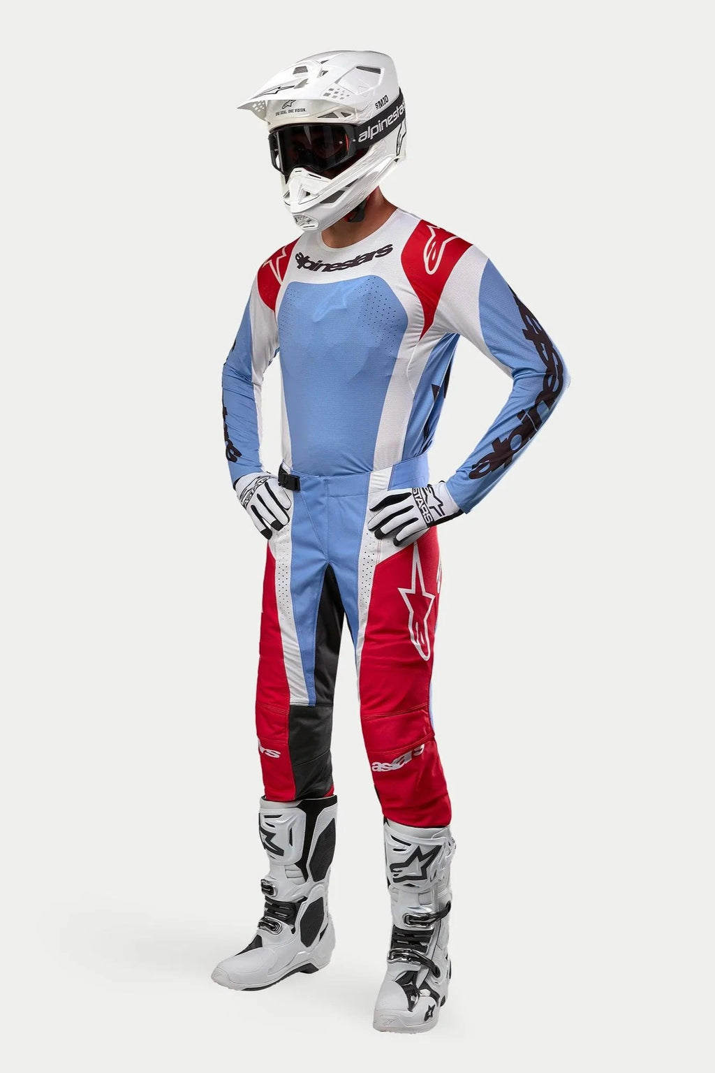 Motocross rider wearing complete racing gear featuring the Alpinestars 2024 Techstar Ocuri Jersey in Light Blue, Mars Red, and White, paired with matching pants, white helmet with goggles, white boots, and white and black gloves.