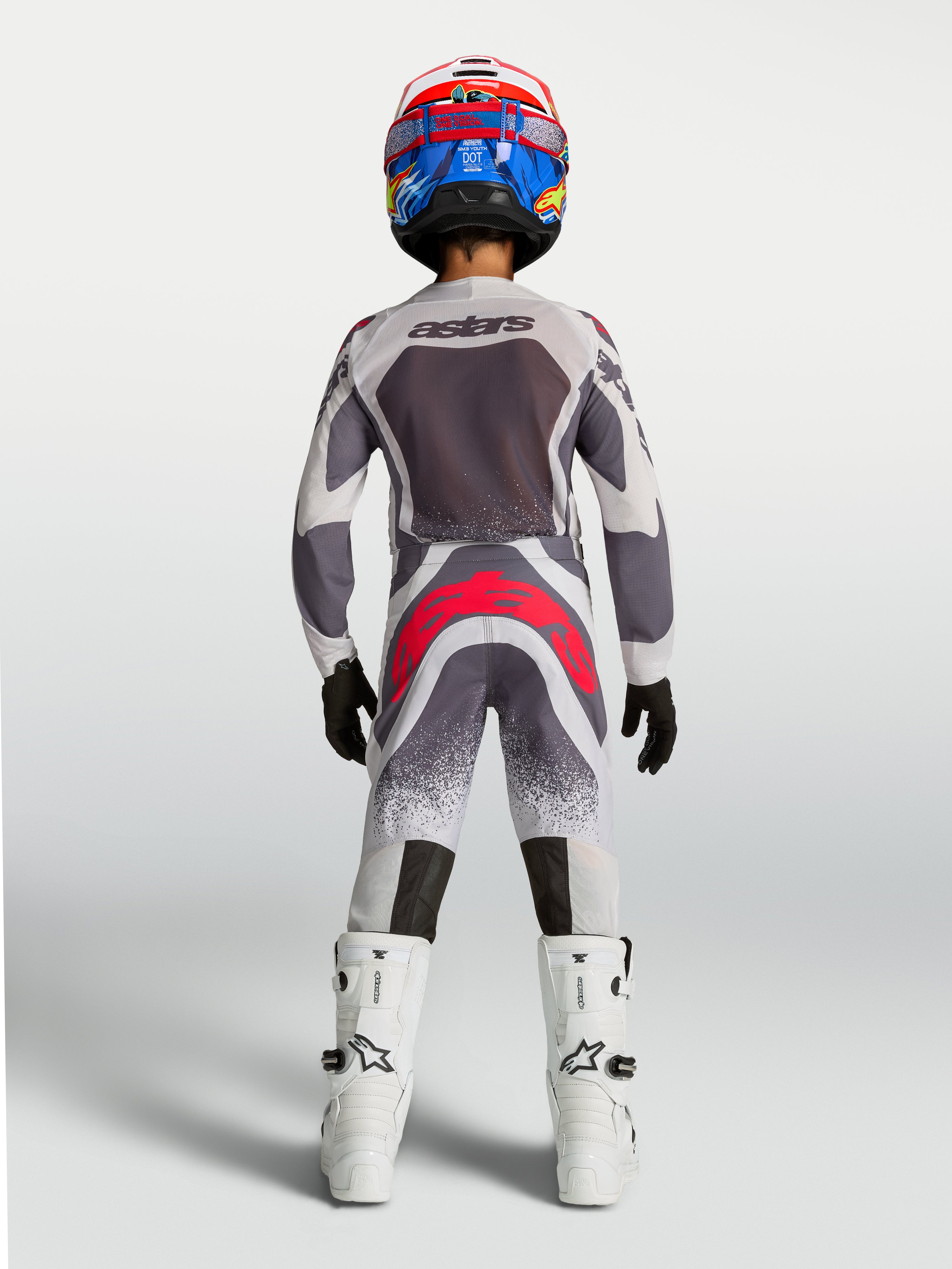 Alpinestars 2027 Ungdom Supertech Swan tröja och utrustningsset, gråa och vita motocrosskläder med röda detaljer, vy bakifrån.