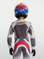 Alpinestars Ungdom Supertech Swan motocrosströja och byxor, grå och vit med röd fluo, vy bakifrån på modell.