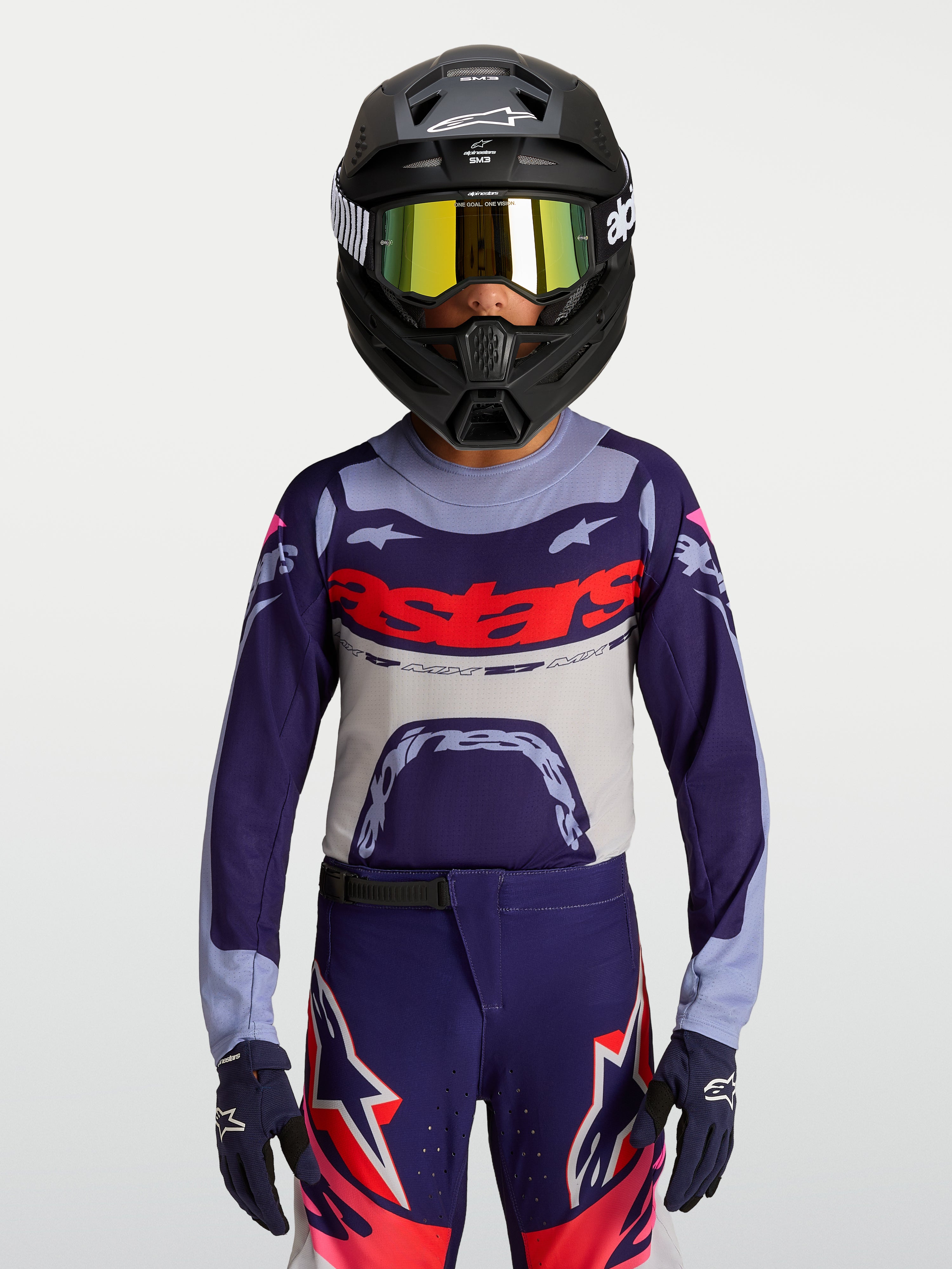 Alpinestars 2027 Supertech Dyna ungdomströja, lila och grå motocrosströja med röd logotyp, atletisk tävlingspassform i stretchmesh för terrängkörning, bärs med matchande byxor och hjälm.