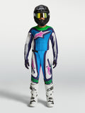 Alpinestars ungdom Supertech Maven utrustningsset, blå och vit motocrossutrustning med gröna och rosa detaljer, bärs av modell med svart hjälm och vita stövlar.