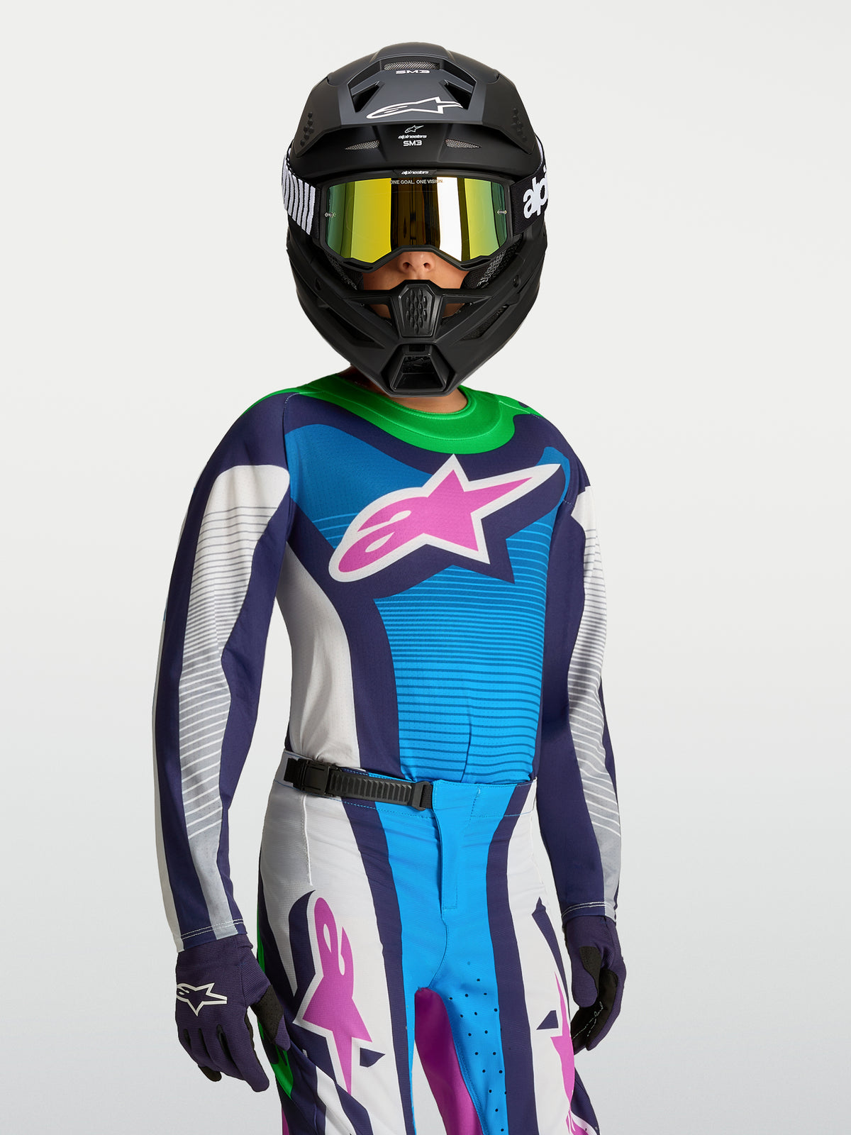 Alpinestars Supertech Maven ungdomströja, professionell motocrosströja i blått och vitt med rosa grafik, stretchmesh för atletisk tävlingspassform, visas på ung förare med matchande utrustning.