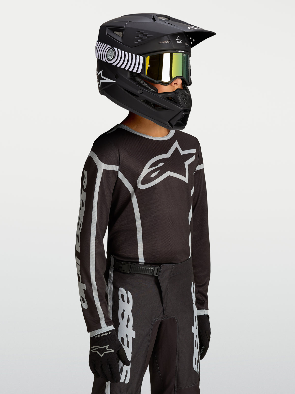 Alpinestars Fluid Apex V2 motocrosströja för ungdom, svart och silver, fukttransporterande material med logotyp på bröstet.