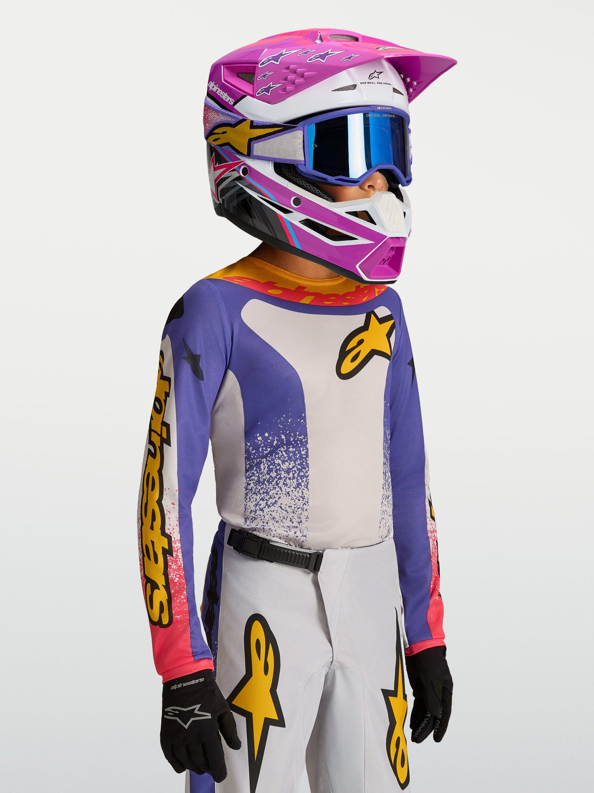 Alpinestars 2027 Ungdom Fluid Drag tröja, blå och vit motocrosströja för barn med gula detaljer, bärs av modell i MX-utrustning.