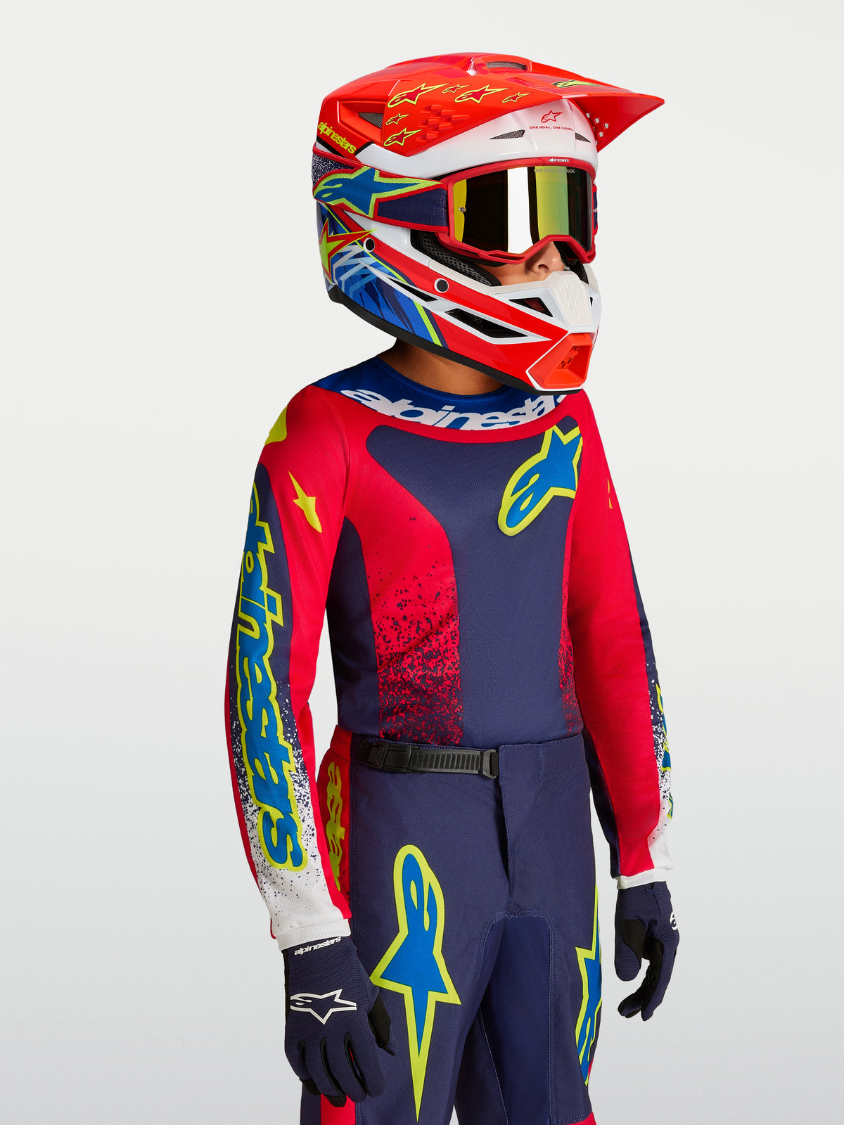 Alpinestars 2027 Fluid Drag ungdomströja, marinblå och eldröd motocrosströja på modell med matchande racinghjälm.