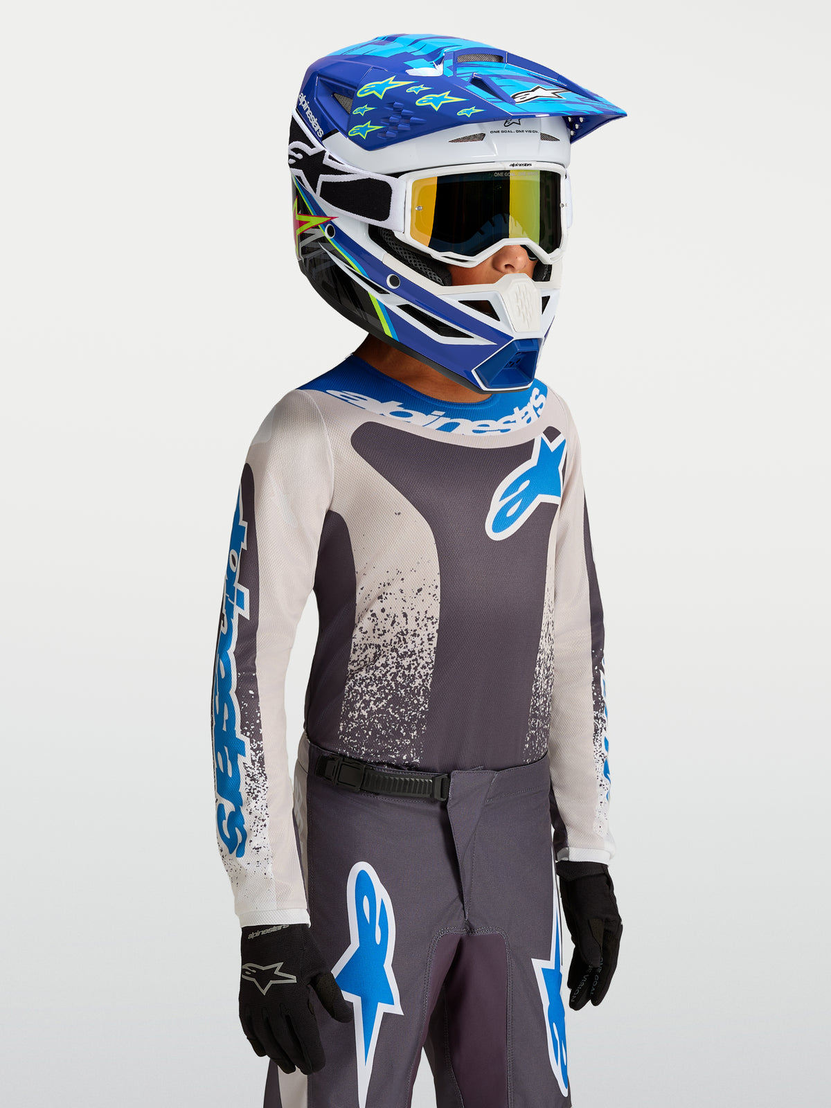 Alpinestars 2027 Ungdom Fluid Drag tröja, motocrosströja för barn i grått och blått, lätt fukttransporterande polytyg, atletisk passform för terrängkörning, bärs med matchande racingutrustning.