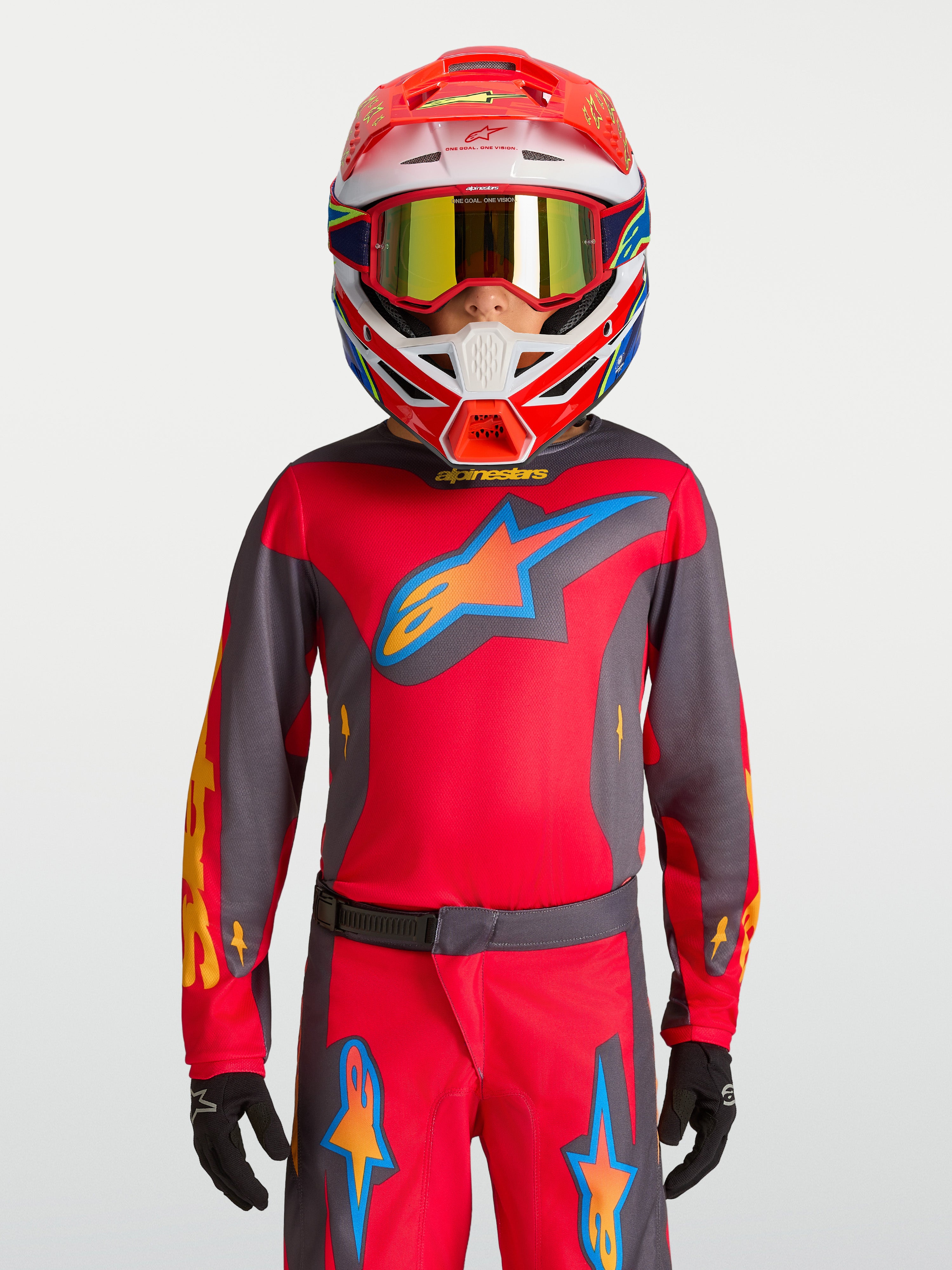 Alpinestars 2027 Fluid Hunt Ungdom Tröja, röd och grå motocrosströja, bärs av modell med racinghjälm för terrängkörning.