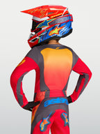 Alpinestars 2027 Fluid Hunt ungdomströja, röd och grå motocrosströja bärs av modell bakifrån med matchande utrustning.
