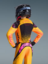 Alpinestars 2026 Supertech Nomur tröja för ungdom, motocrosströja, orange, gul och rosa, vy bakifrån av ungdomsförare med matchande hjälm och byxor, tydlig logotyp och atletisk passform för terrängkörning