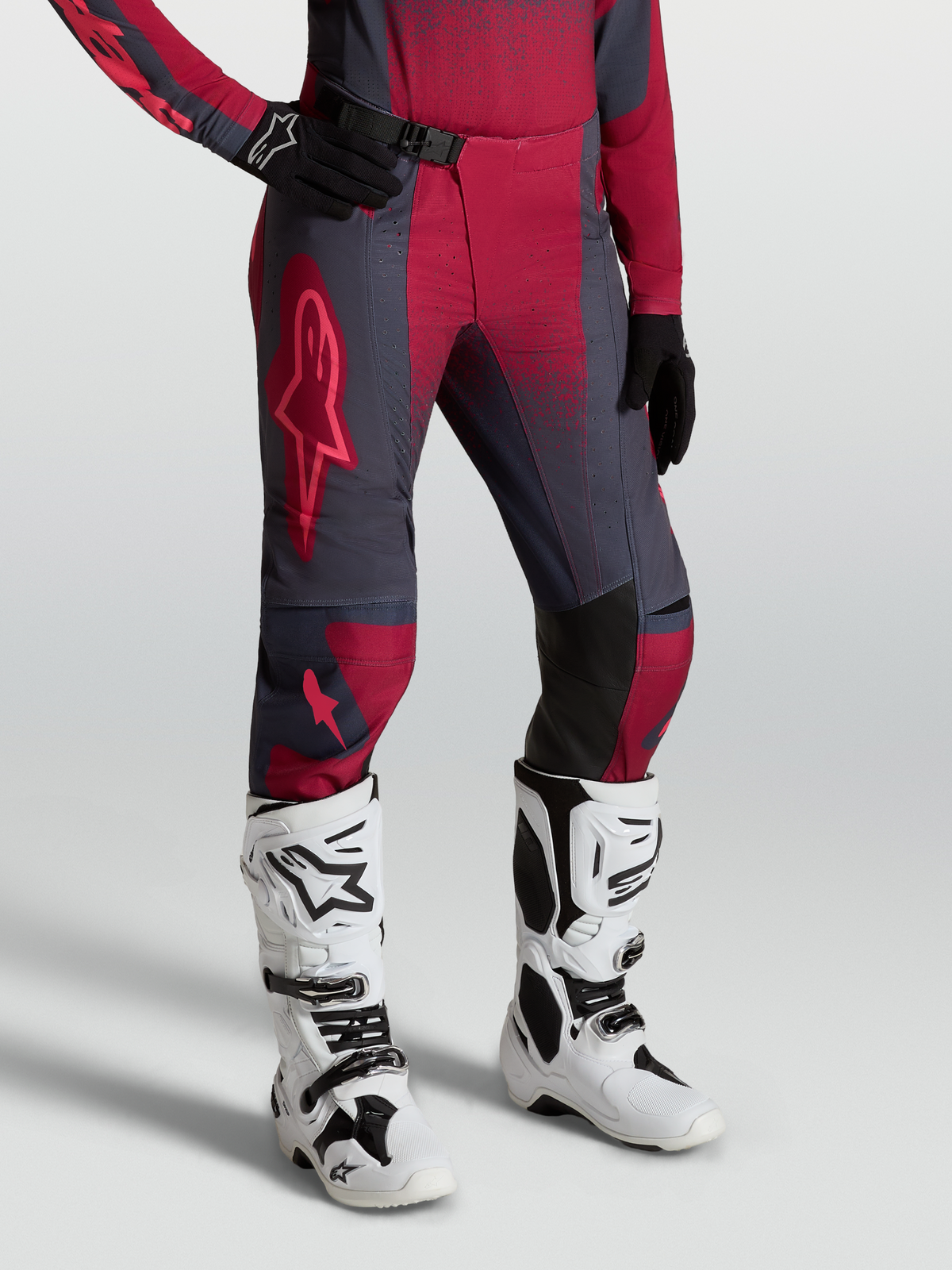 Alpinestars Stella Techstar Swan byxor, röda och mörkgråa motocrossbyxor för damer bärs med vita Tech 10 stövlar.