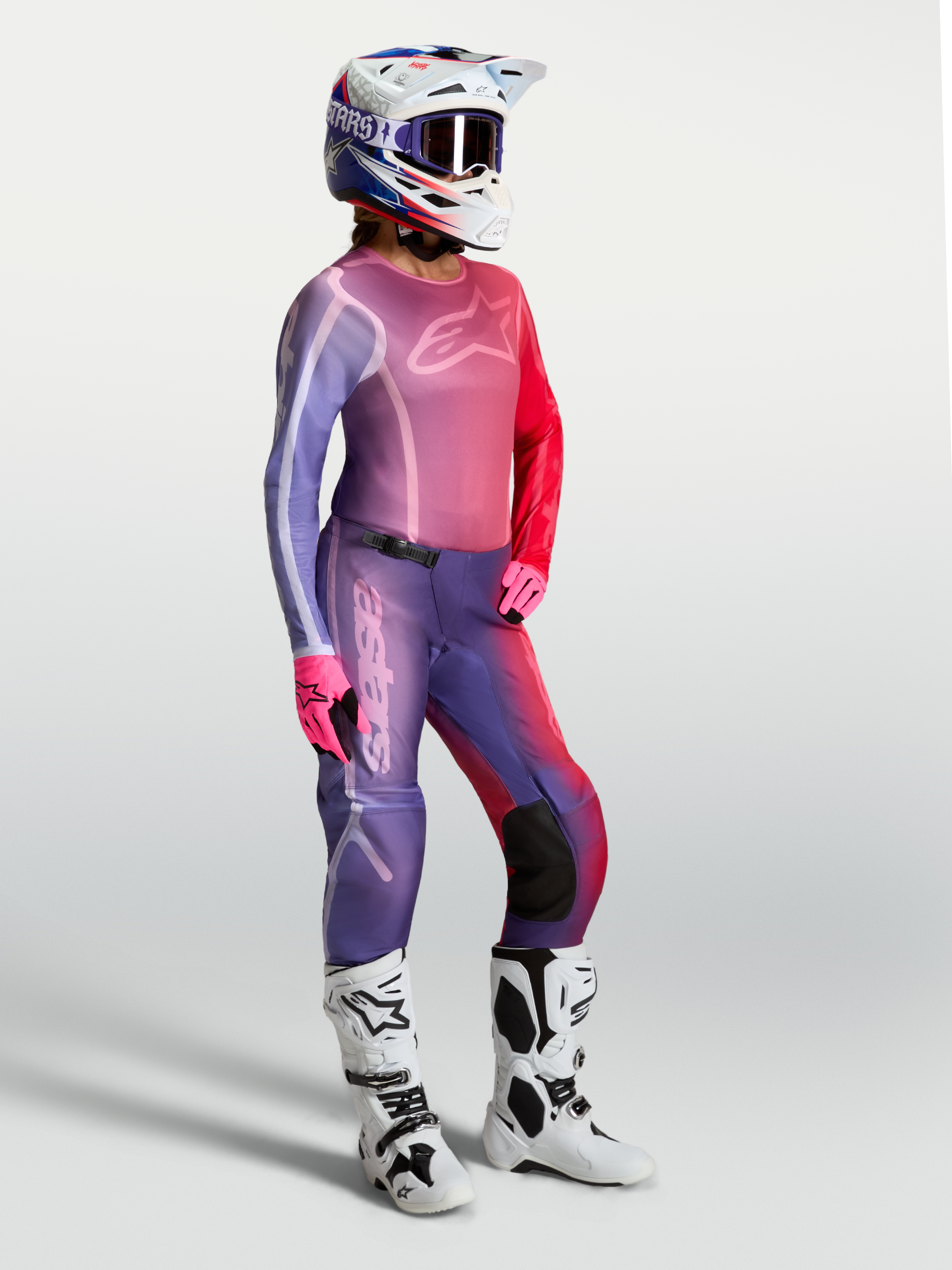 Alpinestars Stella Fluid Kepler tröja, motocrosströja för dam i lila och rött, bärs med matchande byxor och vita stövlar.