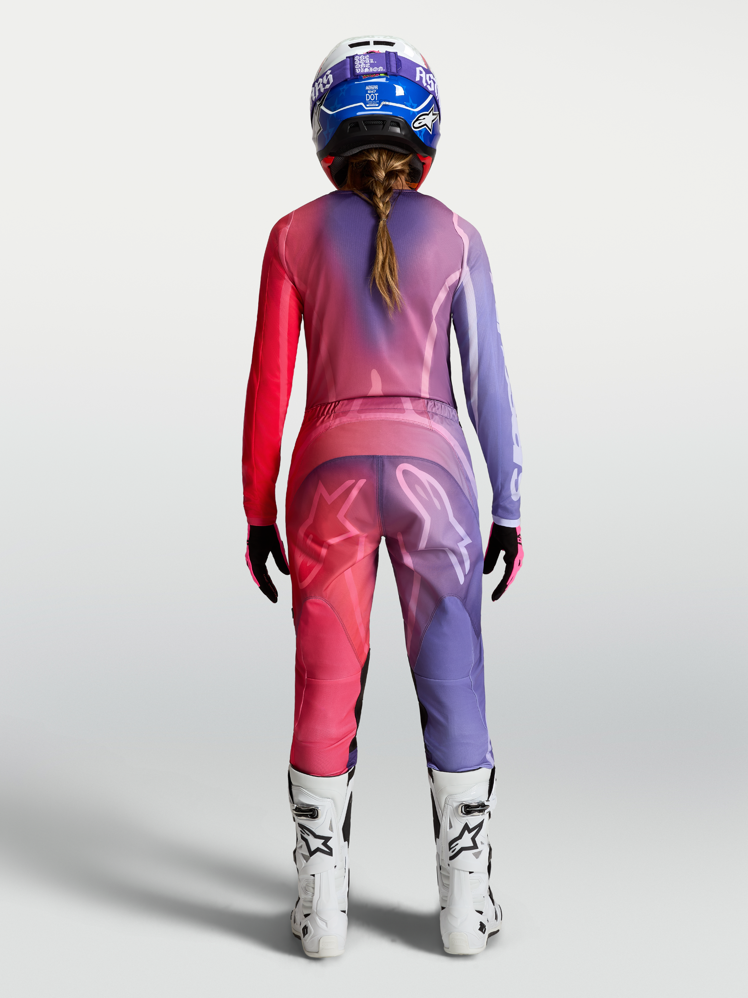 Alpinestars Stella Fluid Kepler tröja, motocrossutrustning för dam, lila och röd, fukttransporterande polytyg, sedd bakifrån på modell med matchande byxor och hjälm.