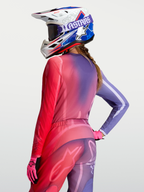 Alpinestars Stella Fluid Kepler tröja, MX-tröja för dam, lila och röd toning, tekniskt polytyg med förlängd rygg, bärs av modell med matchande byxor och hjälm för terrängkörning.
