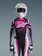 Alpinestars 2026 Stella Techstar Nomur utrustningsset, motocrossoutfit för dam, rosa, svart och vit med stor stjärnlogotyp, innehållande matchande tröja, byxor och handskar med en vit hjälm, sedd framifrån på grå bakgrund