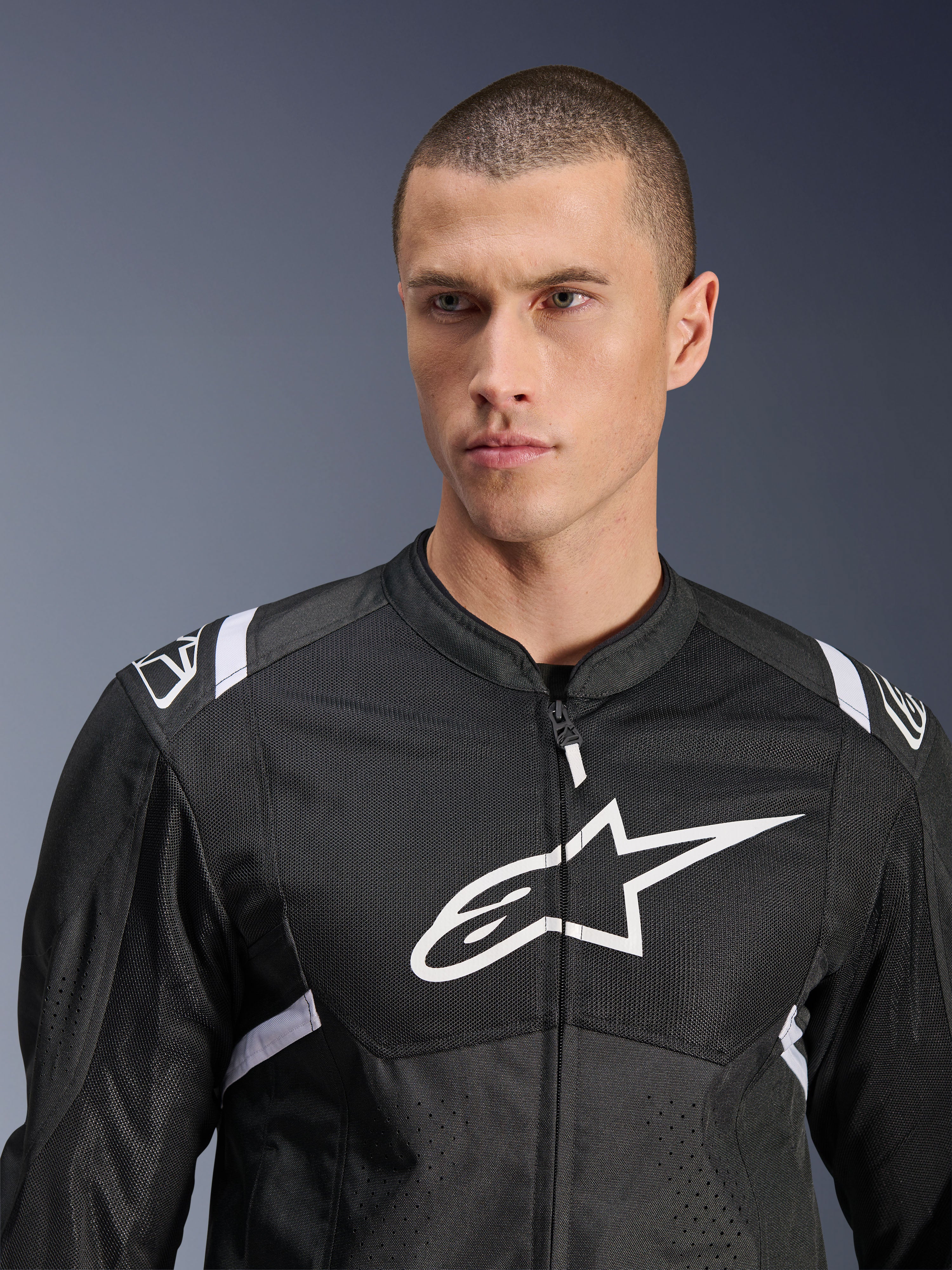 Alpinestars T-SPS Air V2-jacka, motorcykeljacka i textil, svart och vit, med stor vit bröstlogotyp och meshpaneler, sportig passform bärs av manlig modell