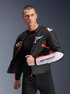 Manlig modell bär Alpinestars T-SPS Air V2-jacka, svart textilmotorcykeljacka med vita och fluorescerande röda detaljer, meshpaneler för luftflöde, vit Alpinestars-logotyp på bröstet och märkesdetaljer på ärmarna, bärs öppen över ett svart baslager