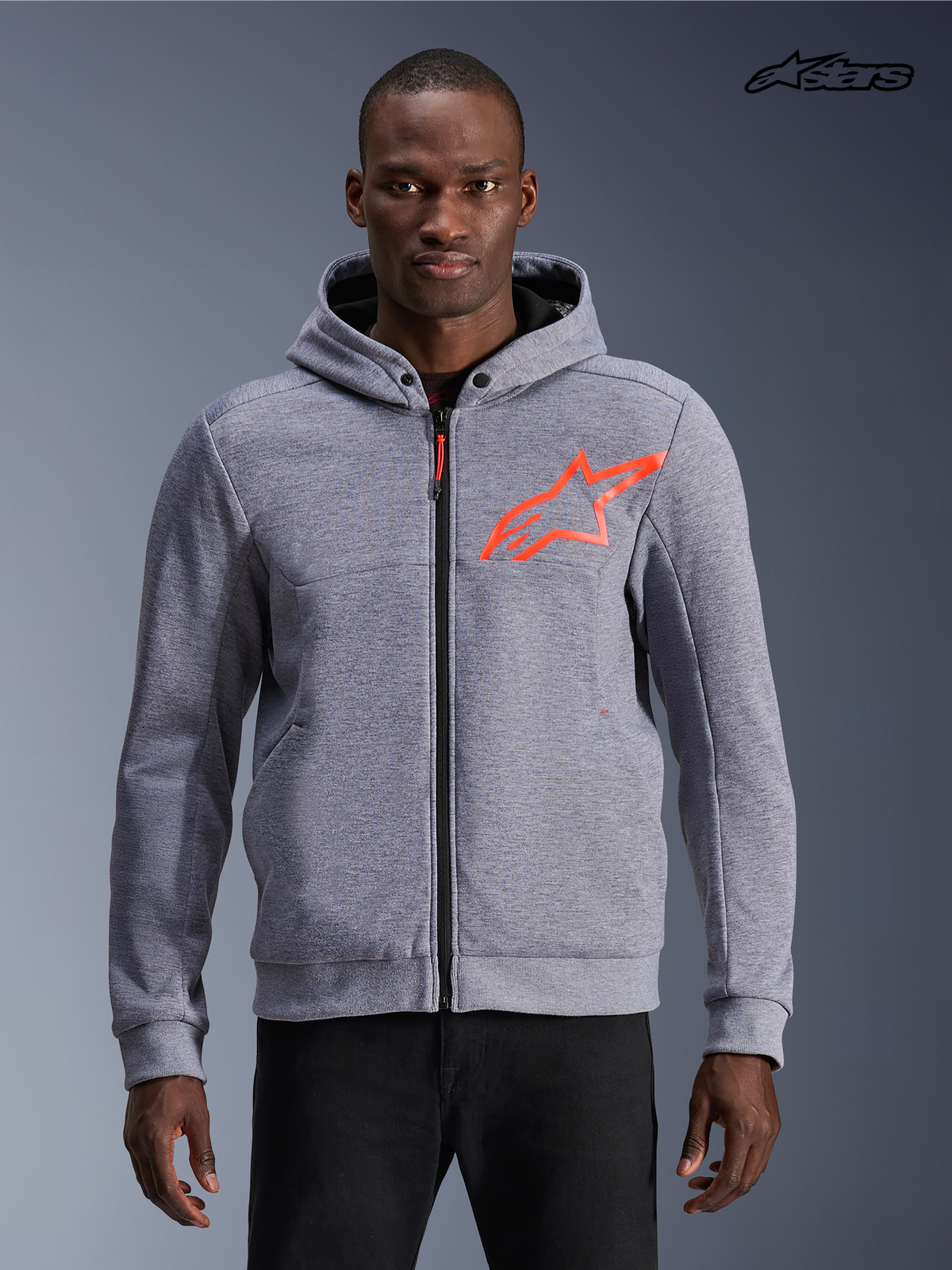 Alpinestars Chrome V2 Sport Hoodie, gråmelerad motorcykeljacka med huva för herr med röda fluo-detaljer, framifrån på modell som visar teknisk fleecekonstruktion och skyddande dragkedja
