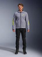Alpinestars Chrome V2 Sport Hoodie, gråmelerad med fluorescerande gula accenter, urban motorcykelutrustning, visas med svarta byxor och svarta mc-skor, teknisk fleece med tydlig gul logotyp på ärmar och bröst, avslappnad streetstyle för mc-körning