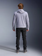 Alpinestars Chrome V2 Sport Hoodie, Gråmelerad Neongul, ryggvy av urban motorcykelutrustning, teknisk huvtröja i fleece buren tillsammans med svarta byxor, med neongula detaljer på ärmarna.