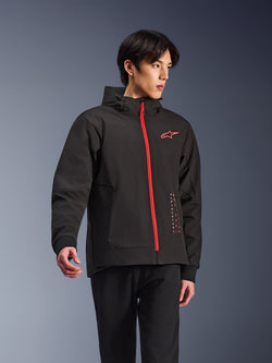 Alpinestars Radium Tech Hoodie, urban motorcykeljacka, svart med klarröd dragkedja, röd Alpinestars-logotyp på bröstet och röd text på sidan, tekniskt vindtätt skal med huva och ribbade muddar, modern street-stil för förare