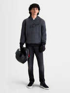 Alpinestars Ageless jacka med huva, urban motorcykeljacka för herr i mörkgrå melange, framifrån på en modell som bär svarta MC-handskar och håller en hjälm, med integrerat skydd på axlar och armbågar