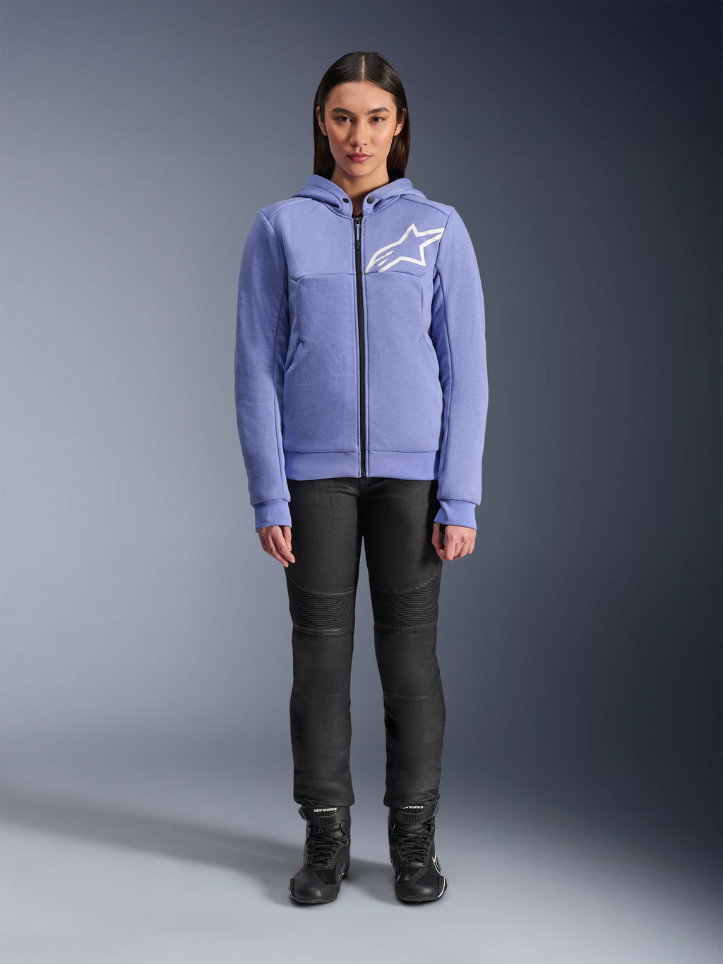 Alpinestars Stella Chrome V2 Sport Hoodie för dam, blåviolett med vit Astars-logotyp på bröstet, teknisk fleece med hel dragkedja och huva, bärs med svarta motorcykelbyxor och körstövlar, avslappnad urban körutrustning för kvinnor