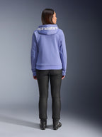 Alpinestars Stella Chrome V2 Sport Hoodie, Blue Violet, ryggvy av en kvinna som bär huvtröjan med vit Alpinestars-logotyp över huvan, kombinerad med svarta byxor och MC-stövlar, urban MC-utrustning i vardaglig stil