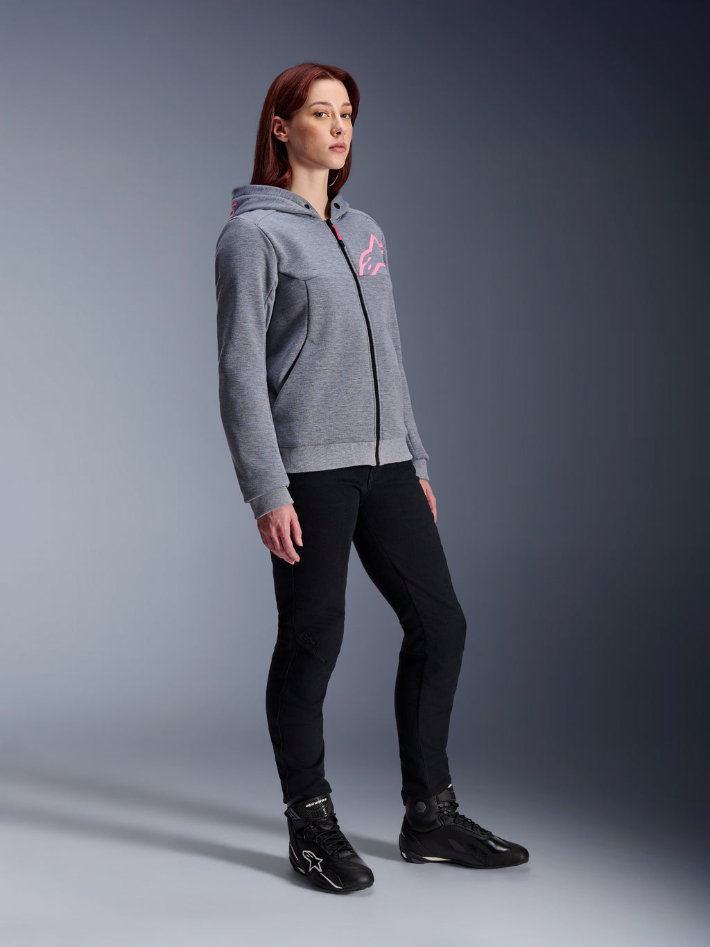 Alpinestars Stella Chrome V2 Sport Hoodie, motorcykeltröja för dam, gråmelerad och neonrosa, bärs med svarta körbyxor och svarta stövlar, avslappnad urban mc-utrustning
