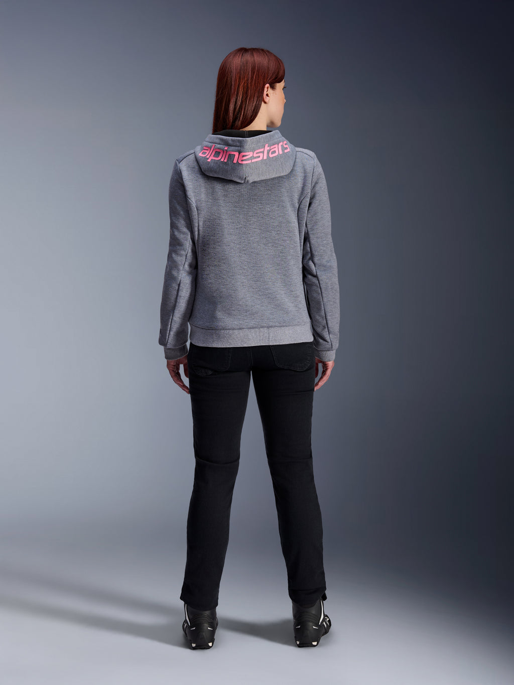 Alpinestars Stella Chrome V2 Sport Hoodie, motorcykelhoodie för dam, gråmelerad och fluorescerande rosa, vy bakifrån som visar rosa Alpinestars-logotyp på huvan, bärs med svarta mc-byxor och stövlar, avslappnad motorcykelutrustning för damer