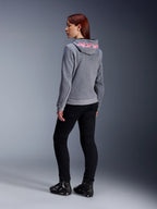 Alpinestars Stella Chrome V2 Sport Hoodie, MC-hoodie för dam, gråmelerad med rosa fluo-logotyp på huvan, vy bakifrån, bärs med svarta byxor och MC-skor, avslappnad urban streetstyle med motorcykelskydd