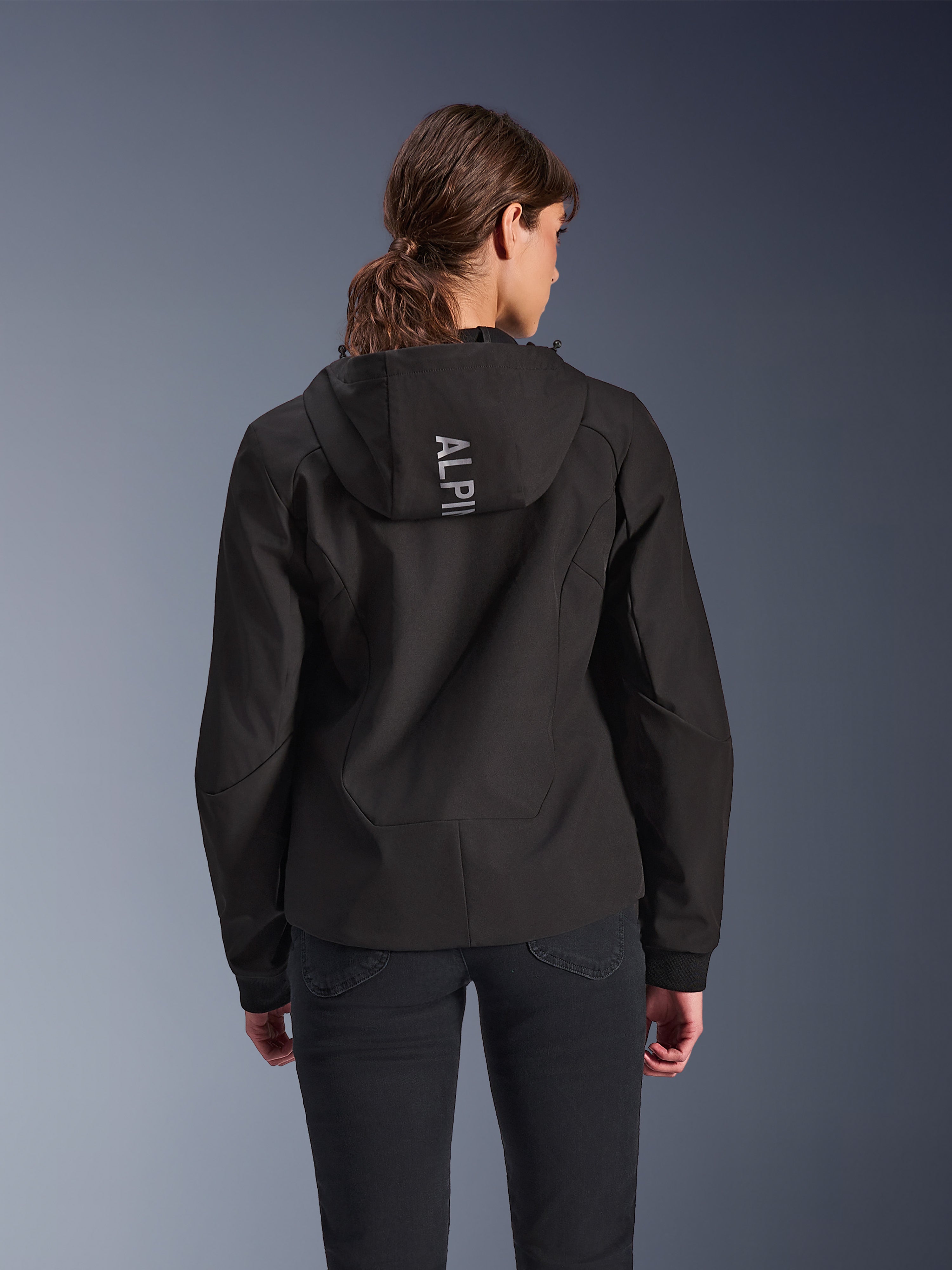 Alpinestars Stella Radium Tech Hoodie, urban mc-huvtröja för damer i svart, vy bakifrån som visar huva med vertikal Alpinestars-logotyp i silver, lätt 3-lagers vindtätt tekniskt skal, modern atletisk passform