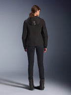 Alpinestars Stella Radium Tech Hoodie för dam, svart, ryggvy av modell som bär en lätt 3-lagers vindtät teknisk hoodie med Alpinestars-logotyp på huvan, kombinerad med svarta byxor och stövlar, urban motorcykelutrustning