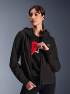 Alpinestars Woman Stella Radium Tech Hoodie, svart huvtröja för stadskörning, kvinnlig modell som visar rött Nucleon Flex Plus-skydd på insidan, lätt 3-lagers vindtätt tekniskt skal med ribbade muddar och logotypmärke på bröstet, skyddande motorcykelutrustning