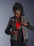 Alpinestars Woman Stella Radium Tech Hoodie i mörkgrått och svart, modell som demonstrerar det löstagbara röda Nucleon Flex Plus-skyddet, urban motorcykelhoodie med rosa dragkedjedetaljer.