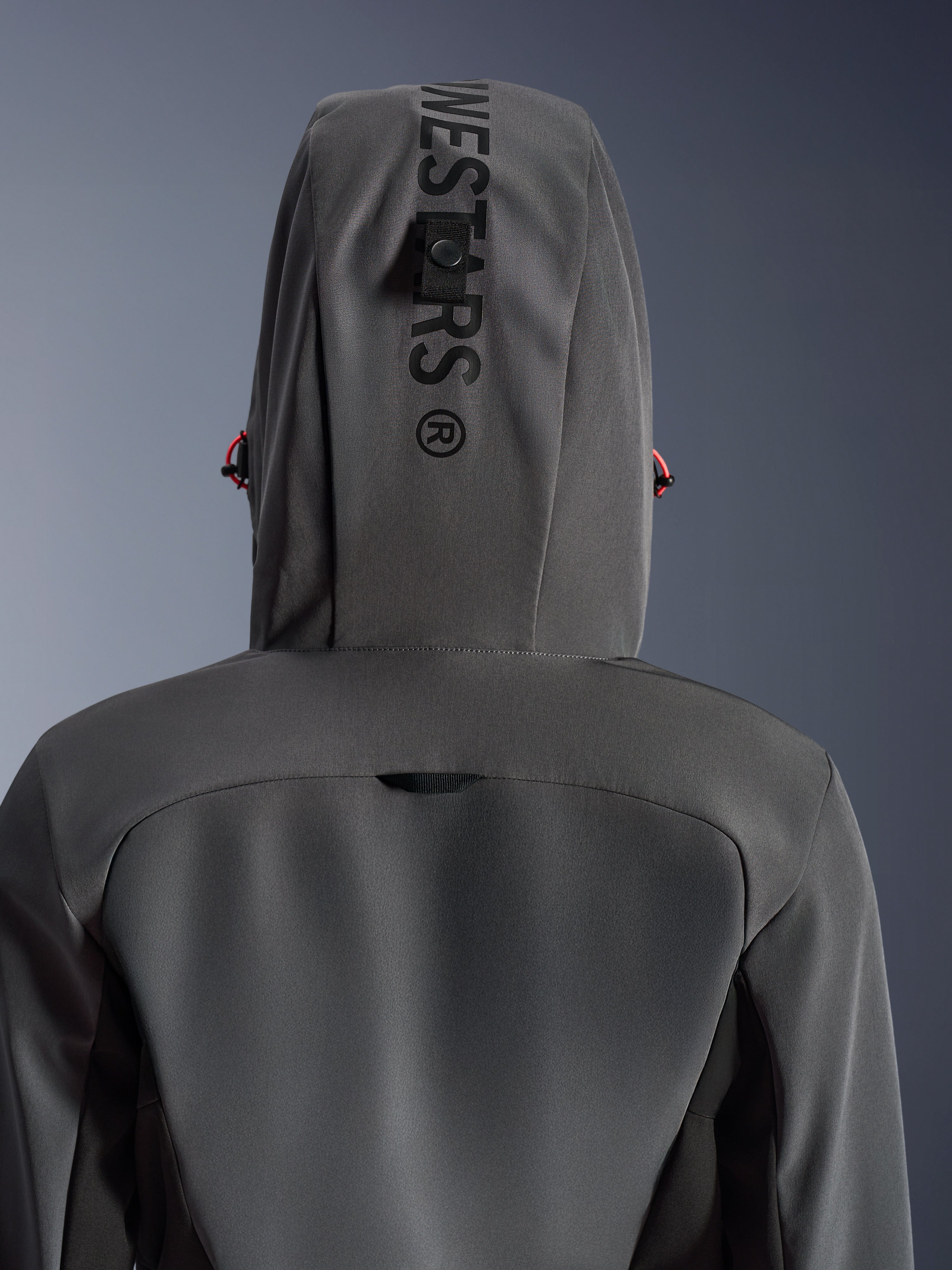 Alpinestars Woman Stella Radium Tech Hoodie, Deep Gray Black, närbild bakifrån som visar huvan med vertikal branding och fästögla, röda detaljer på dragsnören, hållbar 3-lagers vindtät textilkonstruktion för stadskörning på motorcykel.