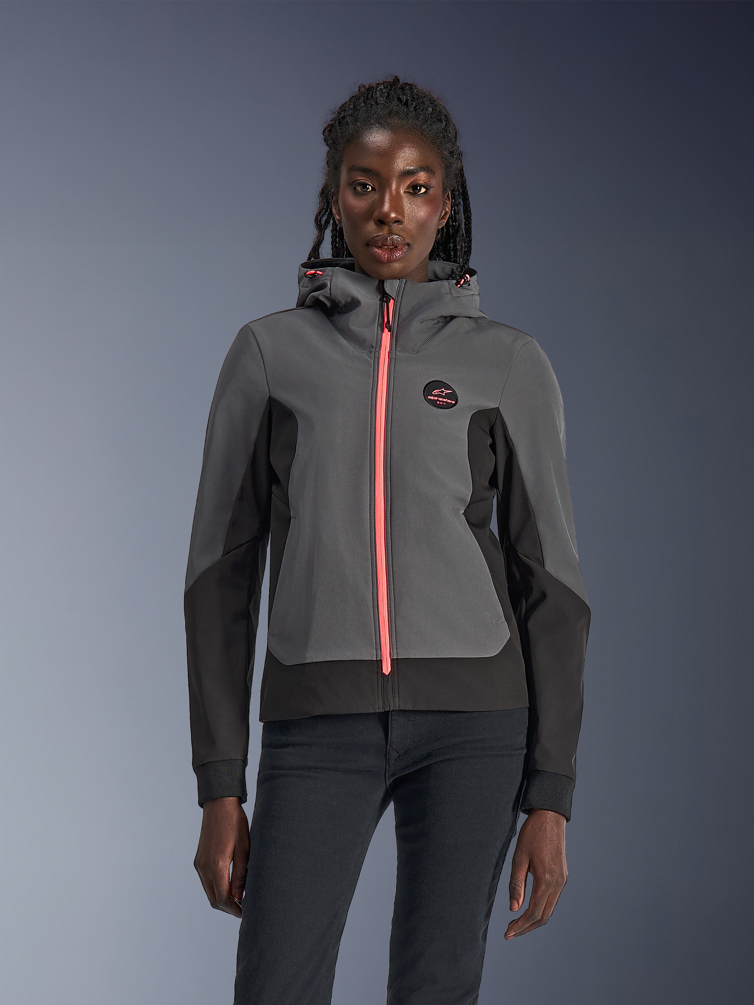 Alpinestars Stella Radium Tech Hoodie, motorcykelhoodie för dam, mörkgrå och svart med stark rosa dragkedja och dragskor till huvan, buren av en modell, sportig urban design med Alpinestars logotyp på bröstet