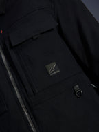 Alpinestars Bryon Water Resistant Overshirt, svart, närbild på vaxat canvastyg, främre dragkedja, bröstficka av cargomodell med Alpinestars logotypmärke och detalj med D-ring i metall