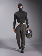 Alpinestars ZX Evo V3 Balaklava, svart, bärs av en modell i ett komplett racing-underställ med matchande långärmad tröja och grå racingbyxor, kolfiberhjälm med skimrande visir, professionell racingutrustning