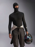 Manlig modell iklädd Alpinestars ZX Evo V3 Balaklava i svart, med vita logotyper på pannan och hakan, kombinerad med en svart långärmad underställströja och hållandes en racinghjälm i kolfiber, professionell flamsäker motorsportutrustning för bilracing.