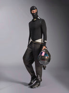 Alpinestars ZX Evo V3 Balaclava, svart, bärs av en förare med komplett underställ för racing, vit logotyp i pannan, föraren håller en kolfiberhjälm med iriserande visir, professionella flamsäkra motorsportkläder.