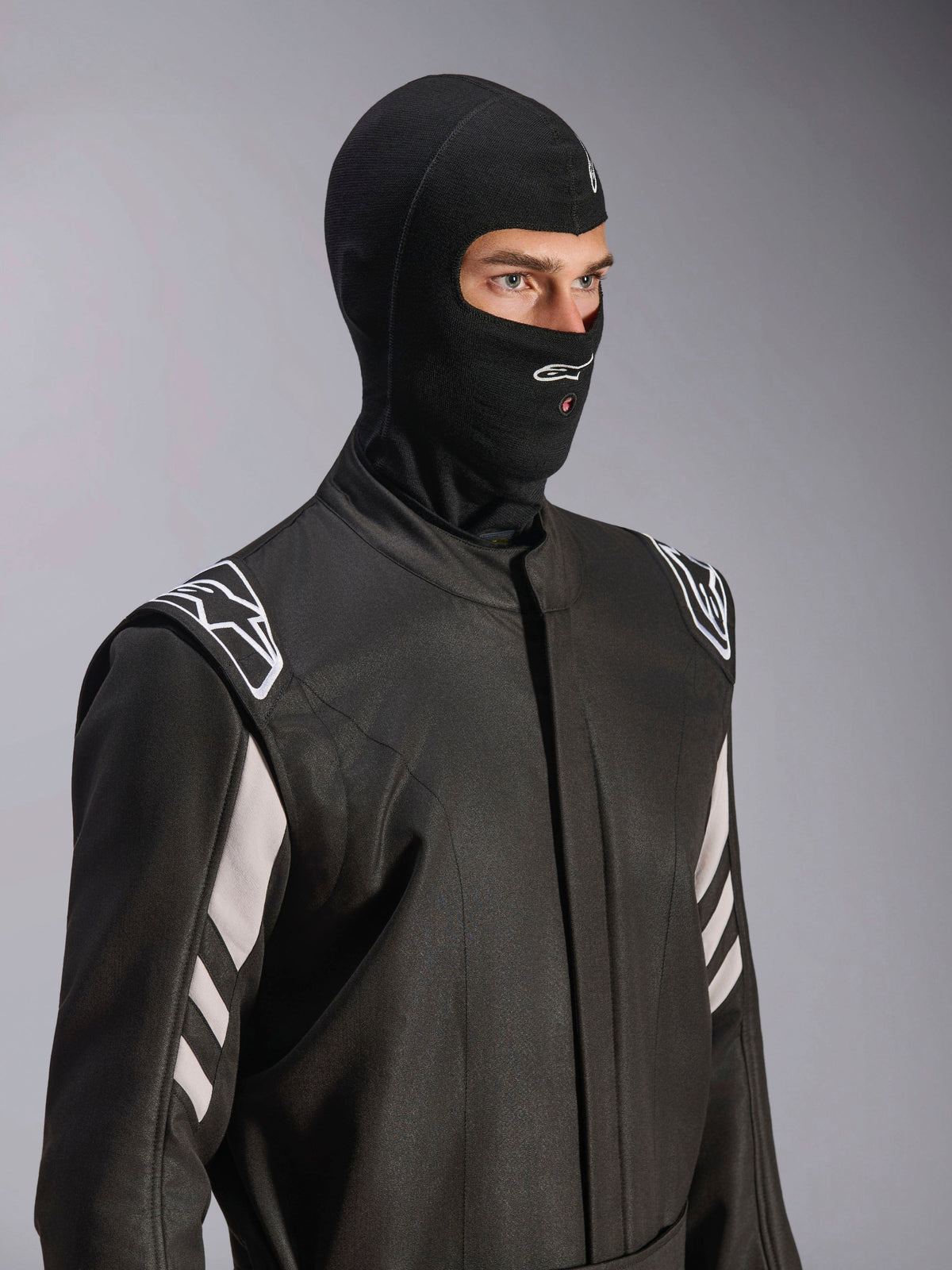 Alpinestars ZX Evo V3 Balaklava, svart, flamsäker huva för bilracing, bärs av en modell i en svart racingoverall med vita detaljer, har Alpinestars-logotyp på hakan, öppning för vätskeslang, professionell skyddsutrustning för motorsport