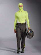 Alpinestars ZX Evo V3 Balaklava i Yellow Fluo, buren med matchande långärmad underställströja och mörkgrå racingbyxor, manlig modell som håller en kolfiberhjälm, professionell racingutrustning