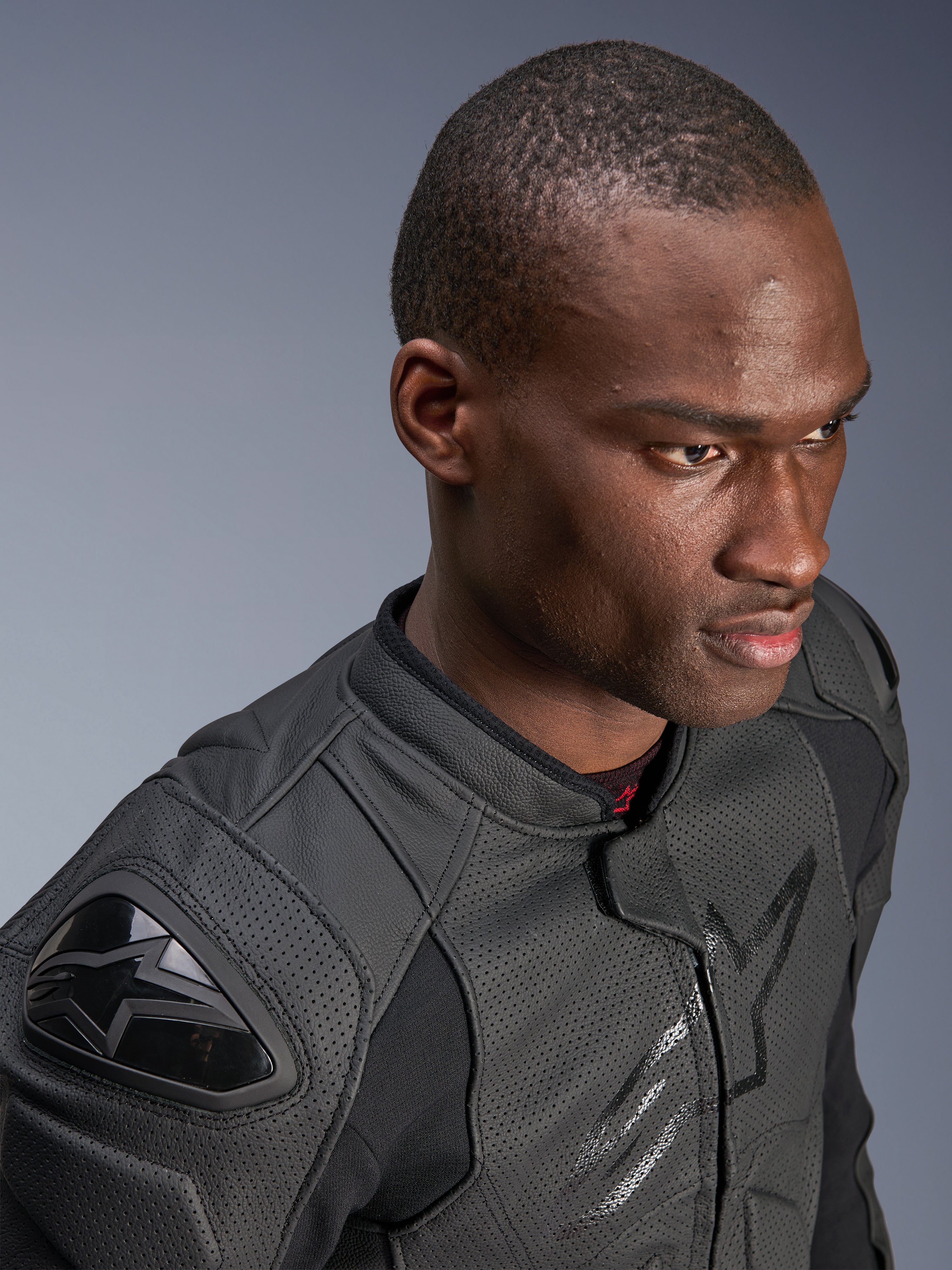 Närbild på en modell som bär Alpinestars Dusk Airflow läderjacka, Black on Black, med omfattande perforerat läder för andningsförmåga, externa DFS-axelskydd och en smidig, modern design för sportkörning.