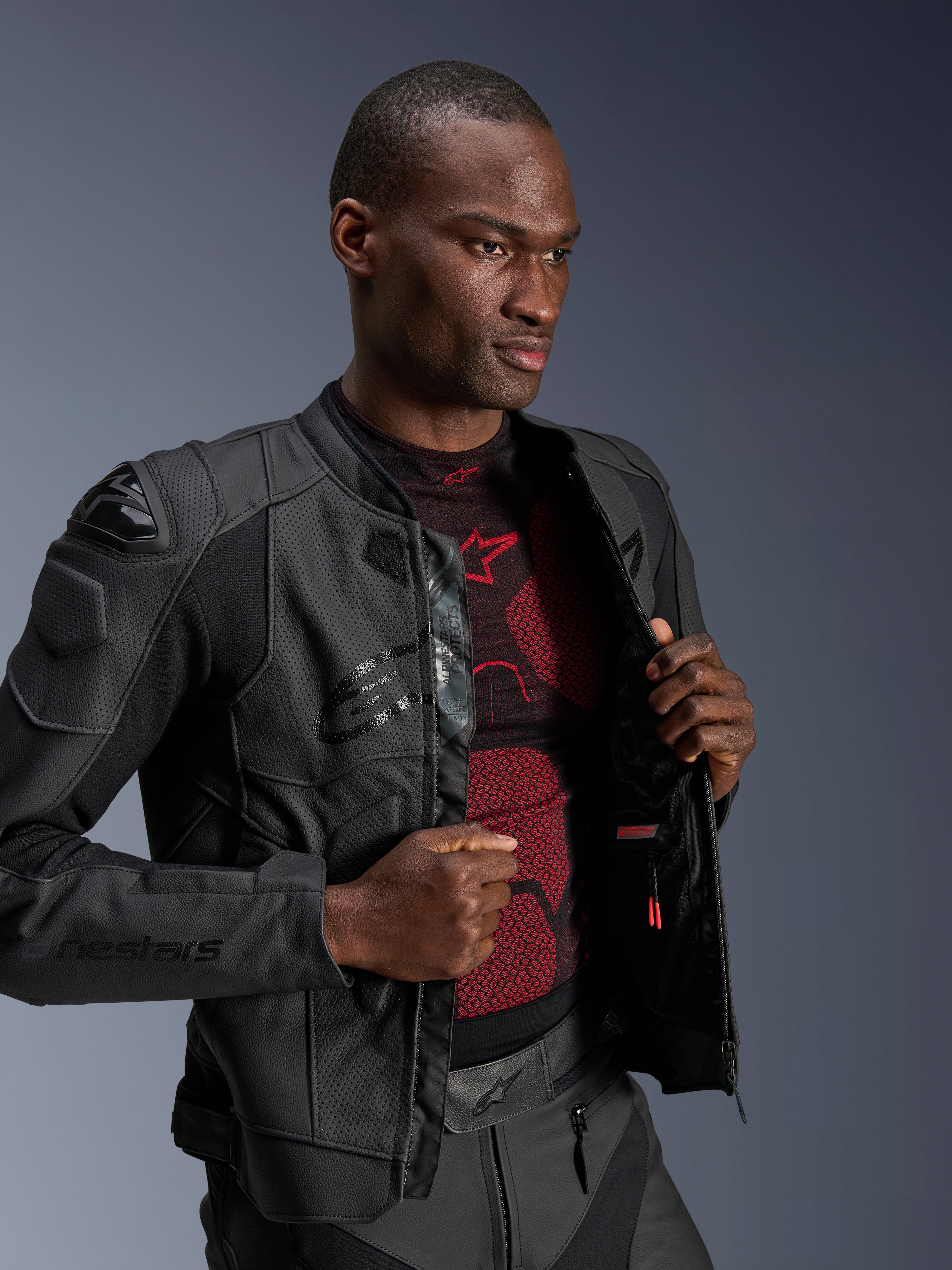 Alpinestars Dusk Airflow läderjacka, Black Black, bärs av en manlig modell över ett rött och svart baslager, med perforerade läderpaneler, externa DFS-axelskydd och en sportig passform.
